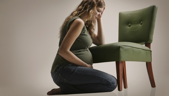 A sad pregnant woman sitting by chair