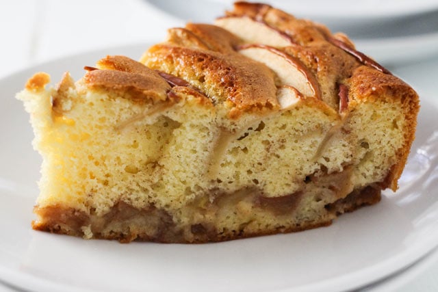 Side view of a slice of sharlotka, Russian apple cake, studded with apples and cinnamon. 