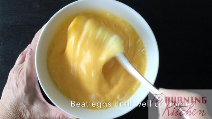beating eggs in white bowl with spoon