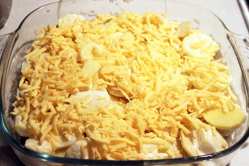 сырые кружочки картофеля, присыпанные тертым сыром, в форме