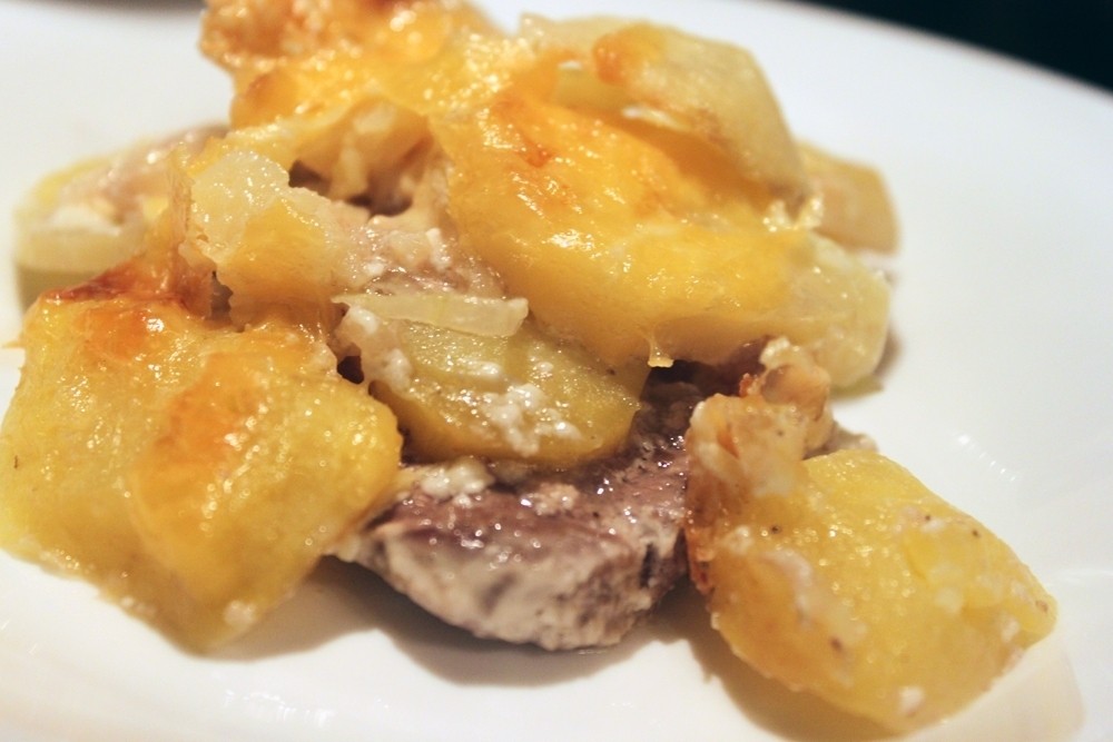 испеченные кружочки картофеля с луком и говядиной на белой плоской тарелке